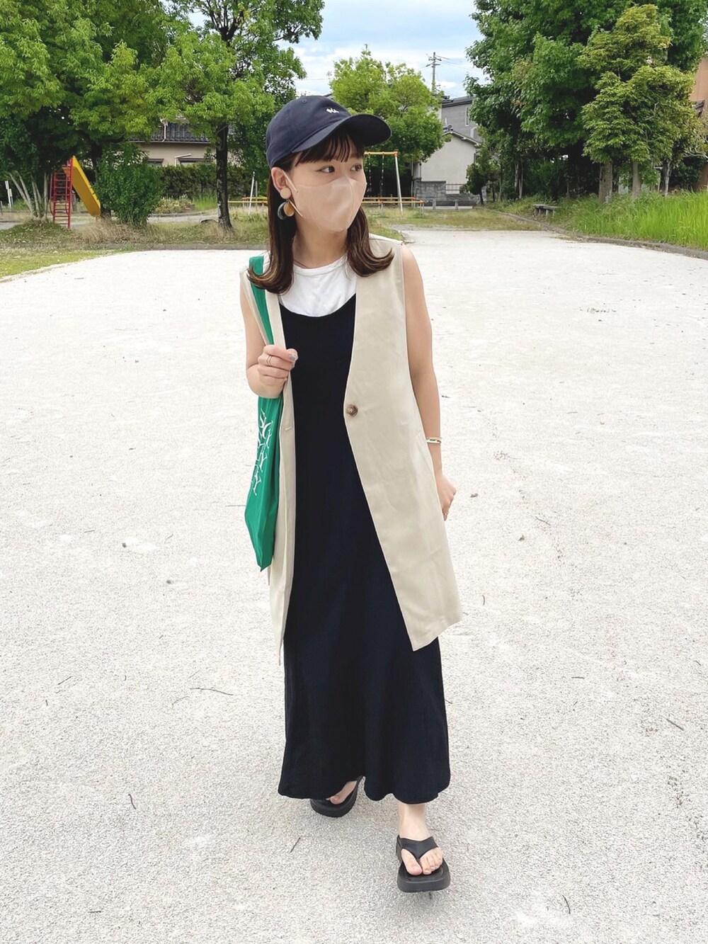 ベージュ系のベスト、ブラック系のワンピース、ブラック系のサンダルを着用したレディースの夏コーディネートの2枚目の写真