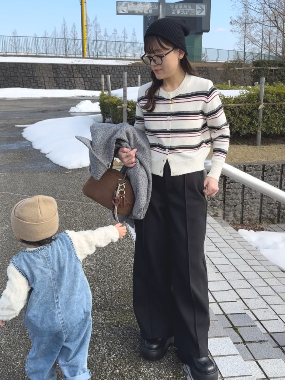 ホワイト系のカーディガン/ボレロ、ブラック系のパンツ、ブラウン系のバッグを着用したレディースの春コーディネートの2枚目の写真