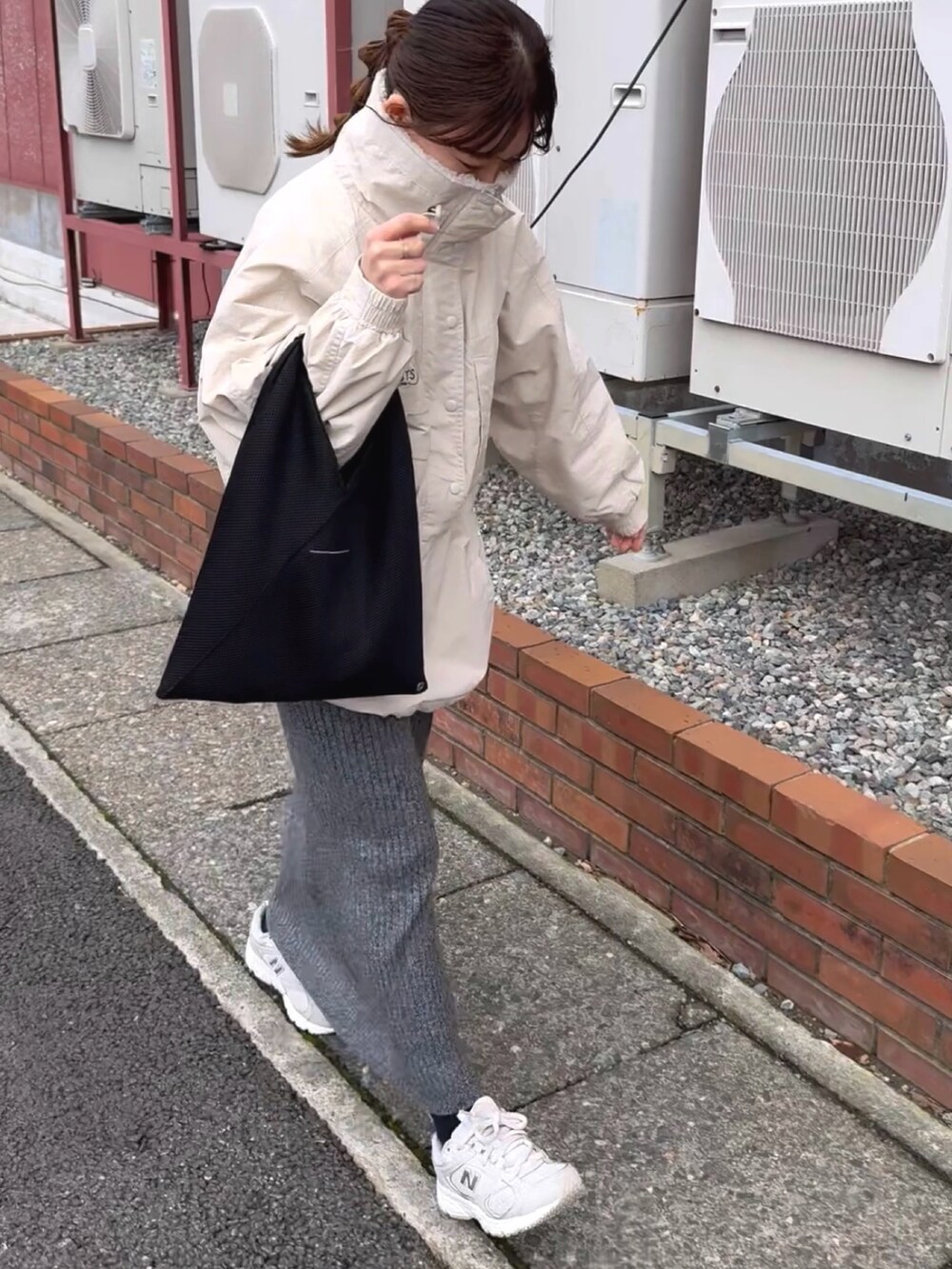 ホワイト系のブルゾン、グレー系のスカート、ブラック系のトートバッグを着用したレディースの冬コーディネートの2枚目の写真