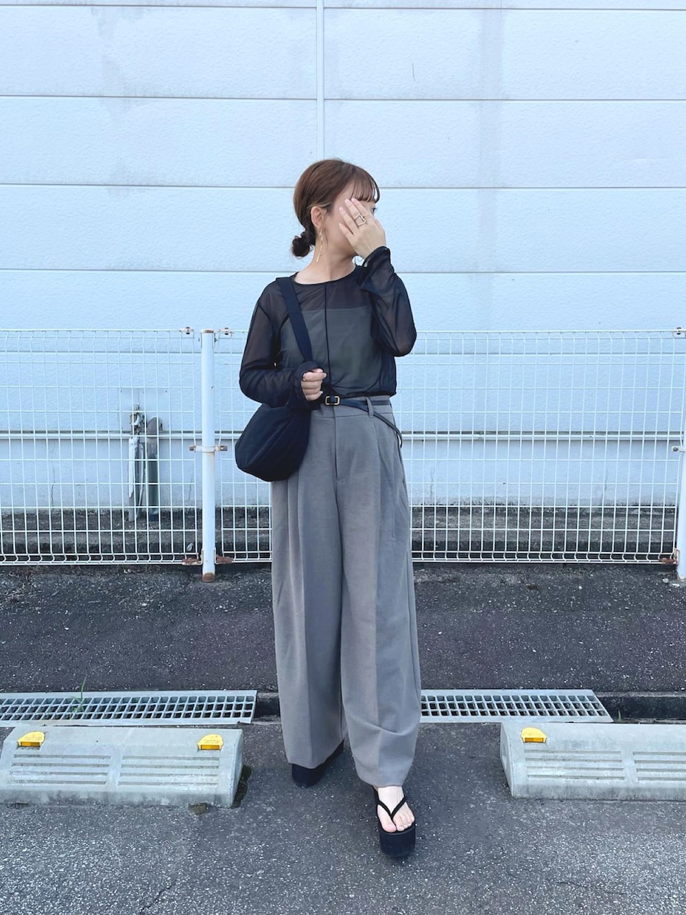ブラック系のトップス、ブラウン系のパンツ、ブラック系のショルダーバッグを着用したレディースの夏コーディネートの2枚目の写真