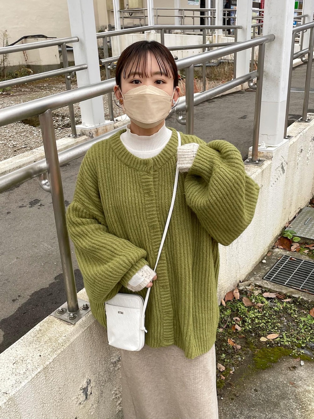 ホワイト系のショルダーバッグ、ホワイト系のニット/セーター、グリーン系のカーディガン/ボレロを着用したレディースの冬コーディネートの5枚目の写真