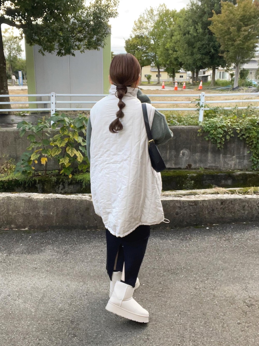 グリーン系のニット/セーター、ホワイト系のジャケット/アウター、ブラック系のバッグを着用したレディースの秋コーディネートの2枚目の写真