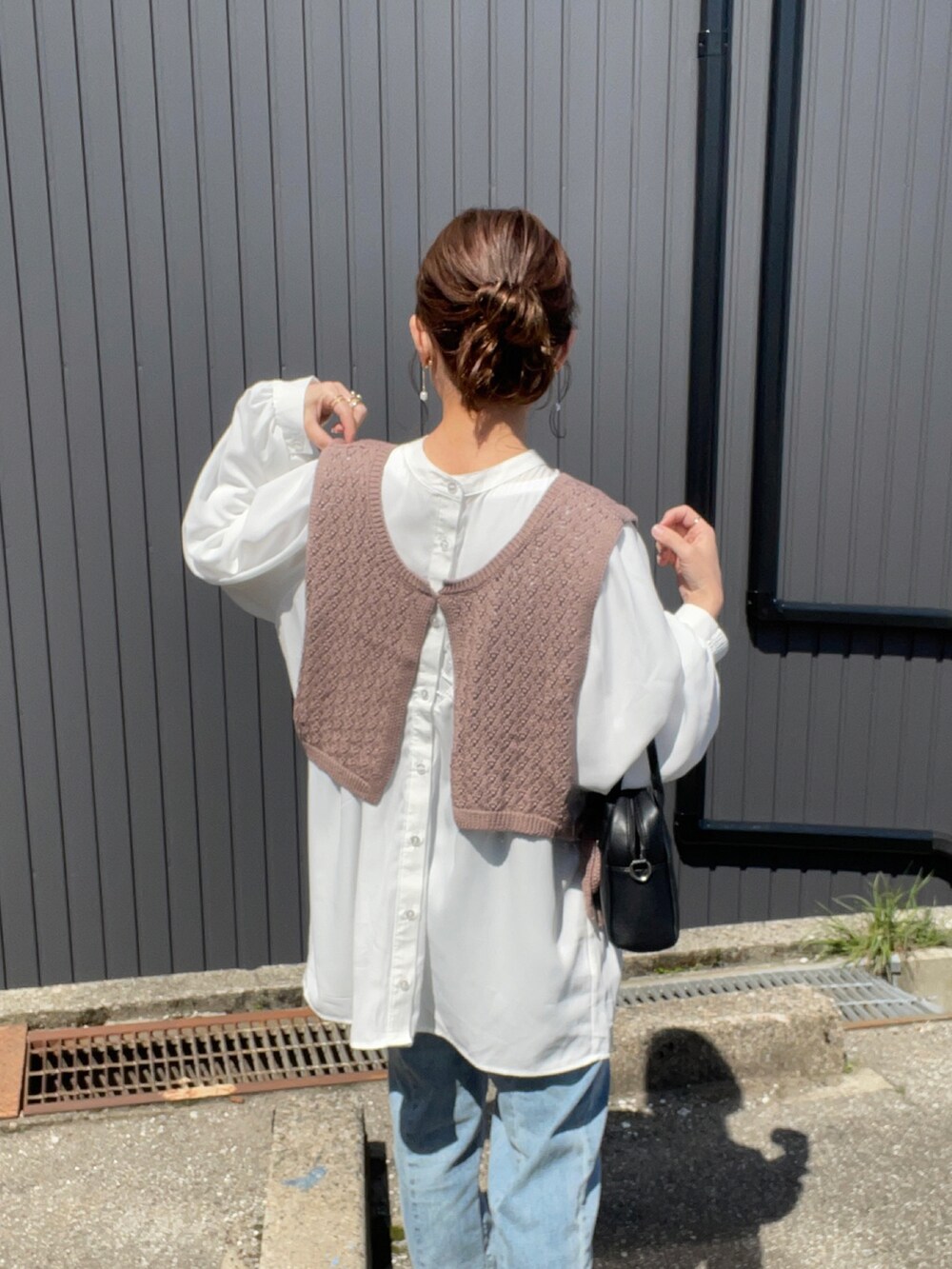 ブラウン系のベスト、ホワイト系のシャツ/ブラウス、ブルー系のデニムパンツを着用したレディースの春コーディネートの3枚目の写真