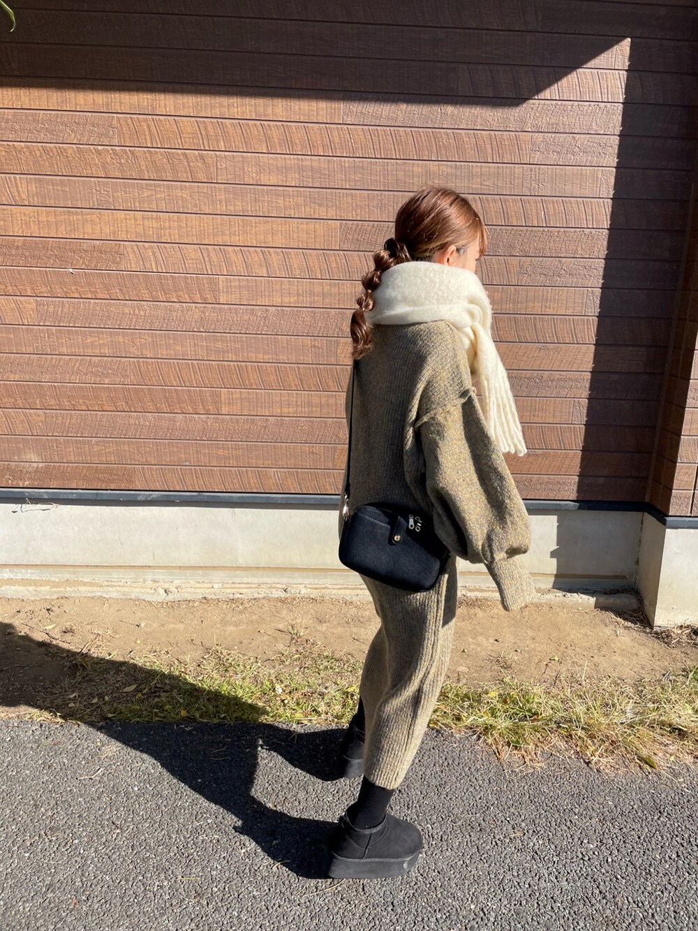 イエロー系のワンピース、ブラック系のショルダーバッグ、ブラック系のブーツを着用したレディースの冬コーディネートの4枚目の写真