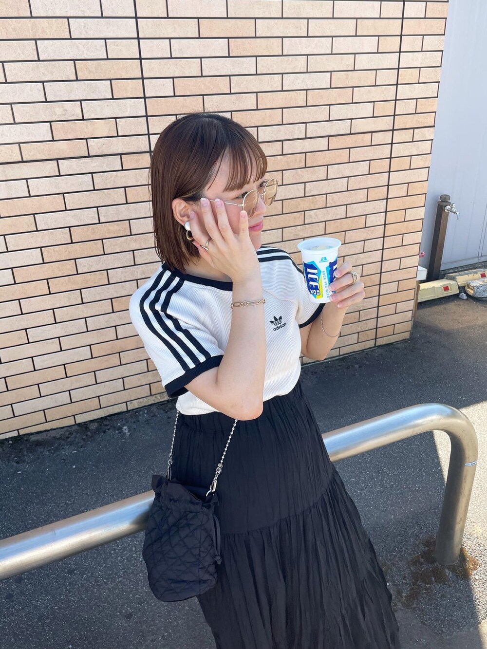 ホワイト系のTシャツ/カットソー、ブラック系のスカート、ブラック系のショルダーバッグを着用したレディースの夏コーディネートの3枚目の写真