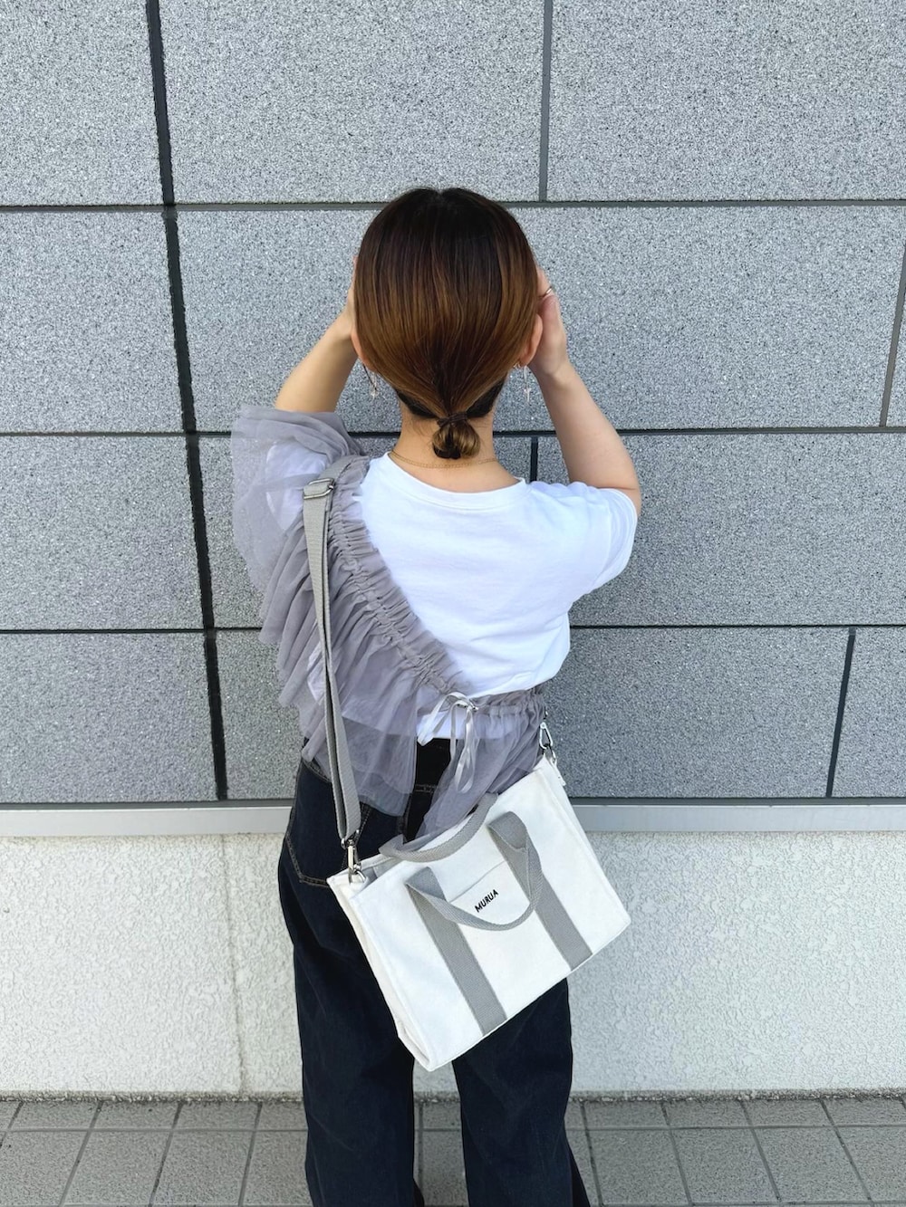 ホワイト系のトートバッグ、グレー系のその他トップス、ブラック系のデニムパンツを着用したレディースの春コーディネートの4枚目の写真