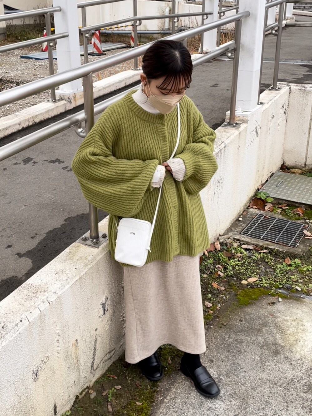 ホワイト系のショルダーバッグ、ホワイト系のニット/セーター、グリーン系のカーディガン/ボレロを着用したレディースの冬コーディネートの3枚目の写真