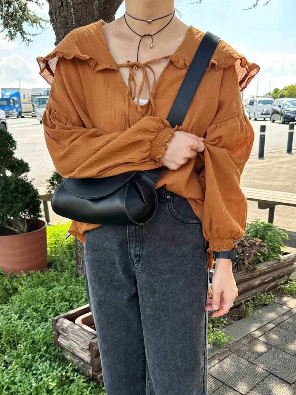 ブラウン系のシャツ/ブラウス、ブラック系のデニムパンツ、ブラック系のショルダーバッグを着用したレディースの秋コーディネートの2枚目の写真