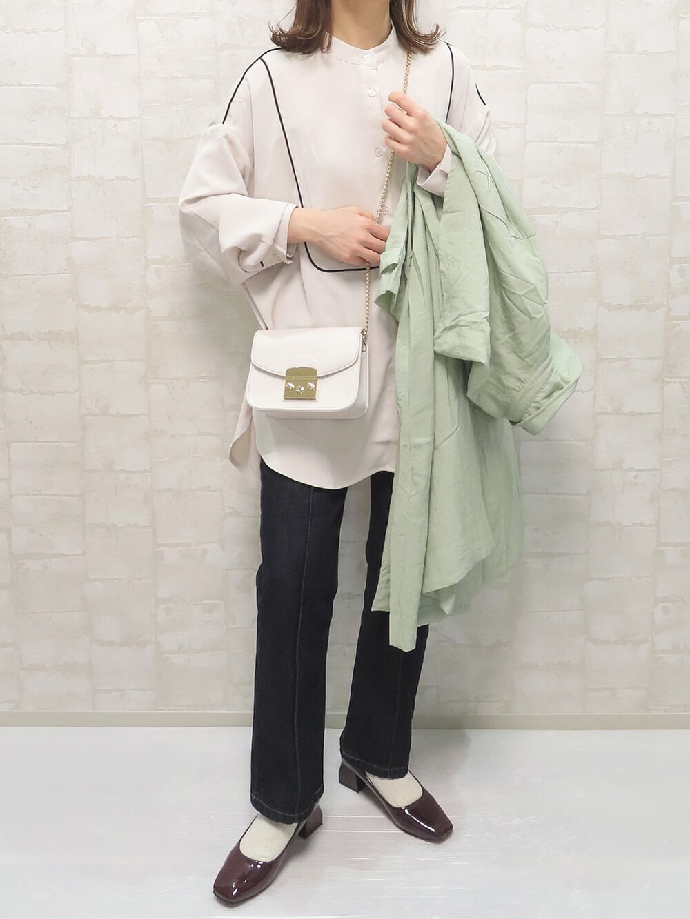 ベージュ系のシャツ/ブラウス、グリーン系のトレンチコート、ブルー系のデニムパンツを着用したレディースの冬コーディネートの3枚目の写真