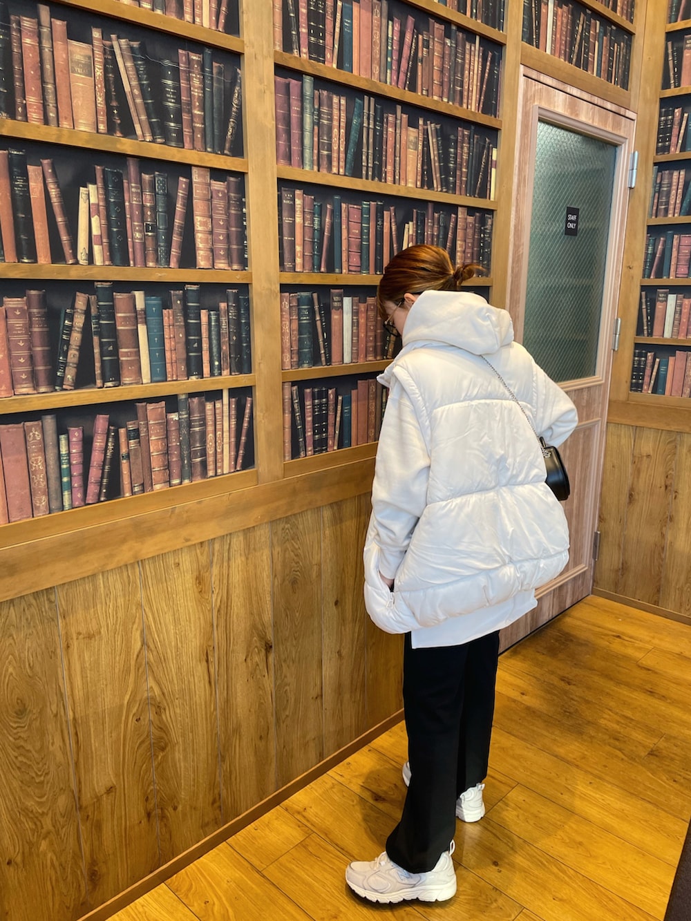 ホワイト系のパーカー、ホワイト系のベスト、ブラック系のショルダーバッグを着用したレディースの冬コーディネートの4枚目の写真