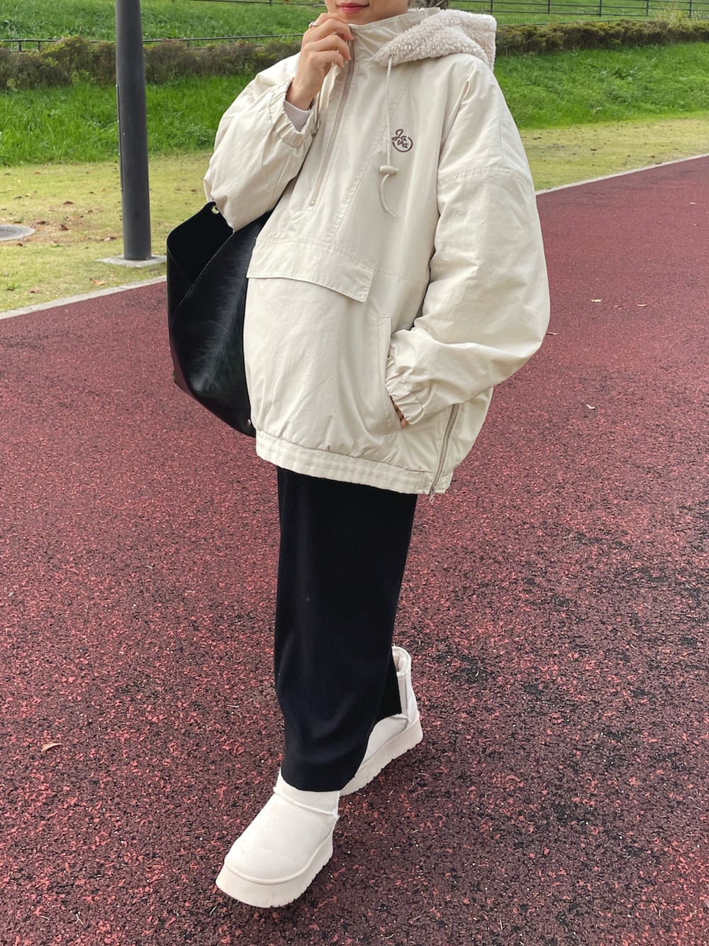 ホワイト系のブルゾン、ブラック系のバッグ、ベージュ系のブーツを着用したレディースの冬コーディネートの2枚目の写真