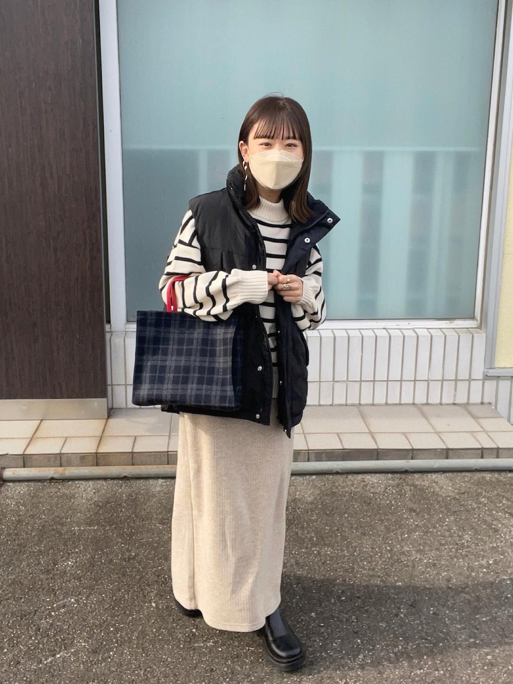 ホワイト系のニット/セーター、ブルー系のトートバッグ、ブラック系のダウンベストを着用したレディースの秋コーディネートの4枚目の写真