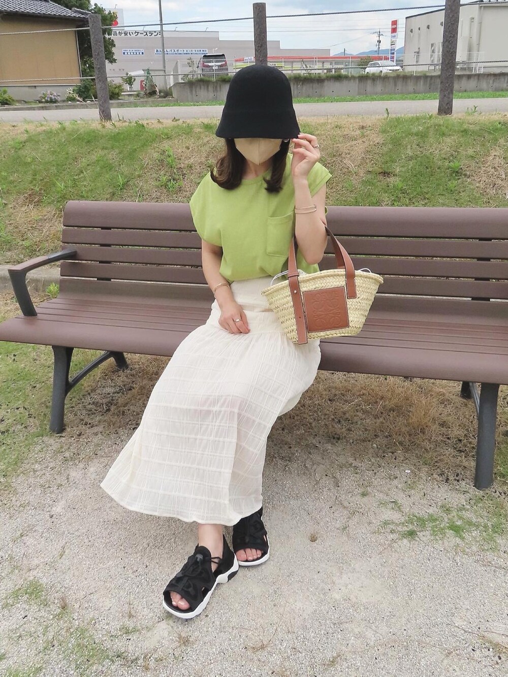 グリーン系のTシャツ/カットソー、ホワイト系のスカート、ベージュ系のかごバッグを着用したレディースの夏コーディネートの4枚目の写真