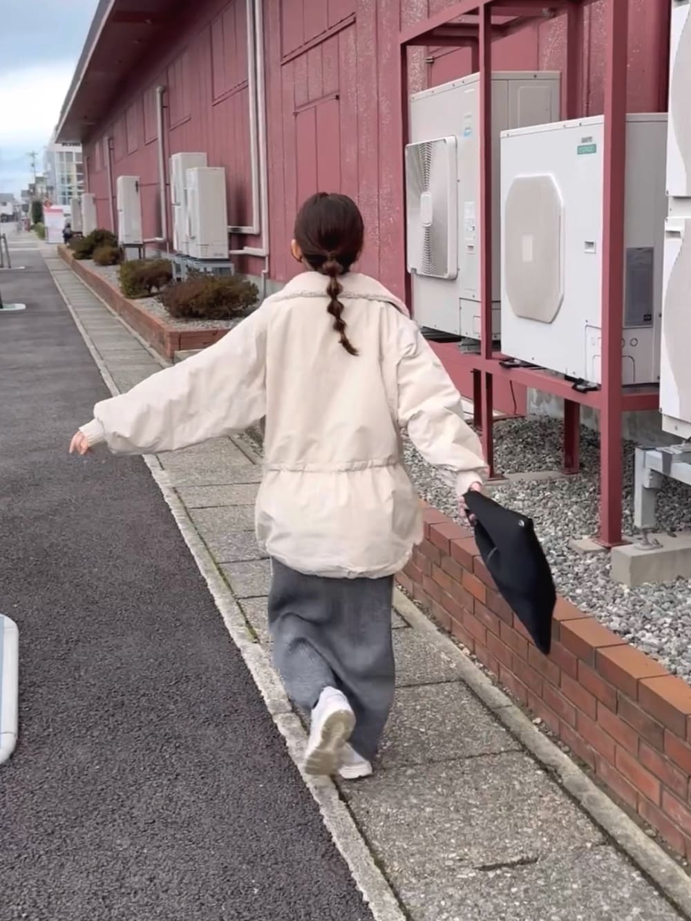 ホワイト系のブルゾン、グレー系のスカート、ブラック系のトートバッグを着用したレディースの冬コーディネートの5枚目の写真