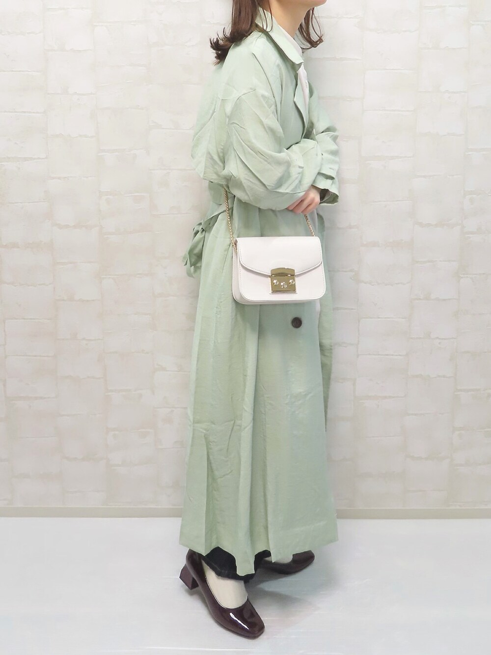 ベージュ系のシャツ/ブラウス、グリーン系のトレンチコート、ブルー系のデニムパンツを着用したレディースの冬コーディネートの2枚目の写真