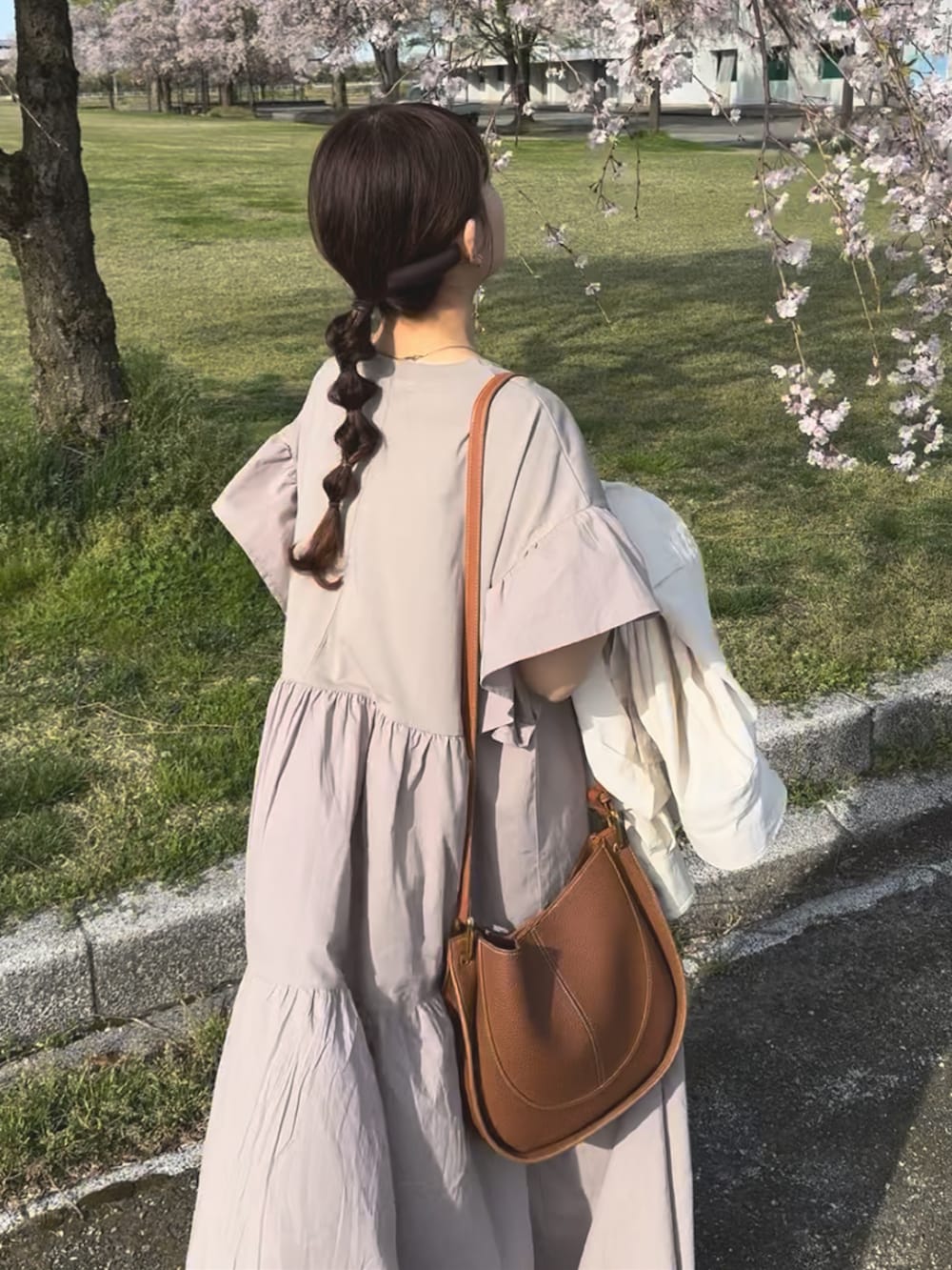 ベージュ系のワンピース、ブラウン系のショルダーバッグ、ブラック系のスニーカーを着用したレディースの春コーディネートの4枚目の写真