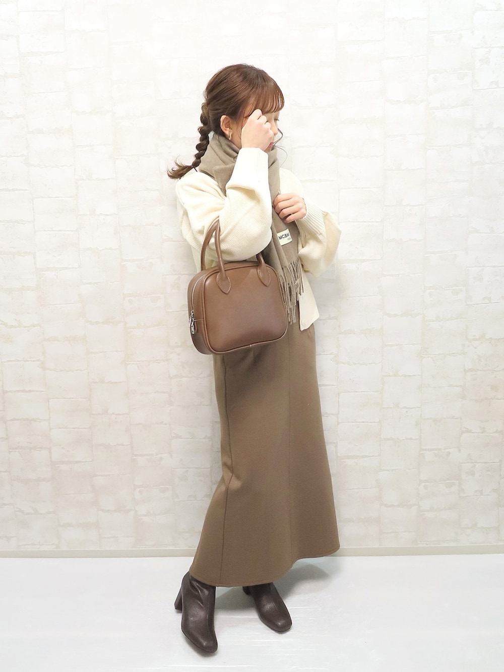 ホワイト系のカーディガン/ボレロ、ホワイト系のニット/セーター、ブラウン系のスカートを着用したレディースの冬コーディネートの2枚目の写真