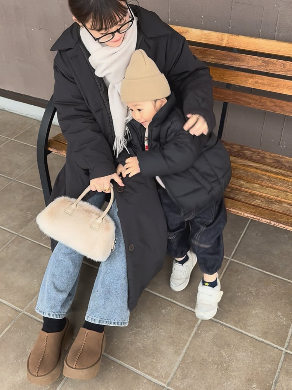 ブラック系のダウンジャケット/コート、ブルー系のデニムパンツ、ホワイト系のバッグを着用したレディースの冬コーディネートの2枚目の写真