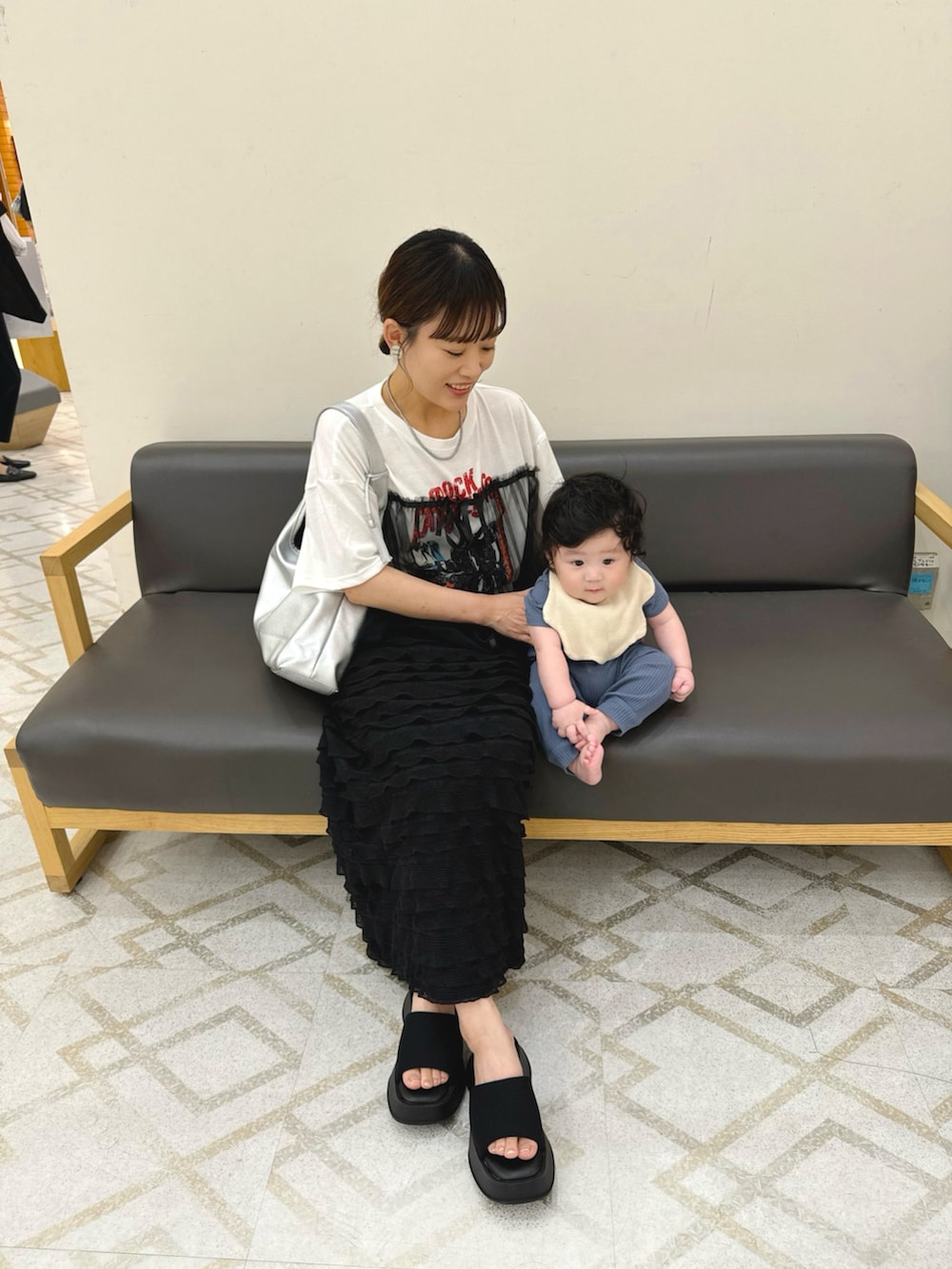 ホワイト系のトップス、ブラック系のスカート、シルバー系のトートバッグを着用したレディースの夏コーディネートの2枚目の写真