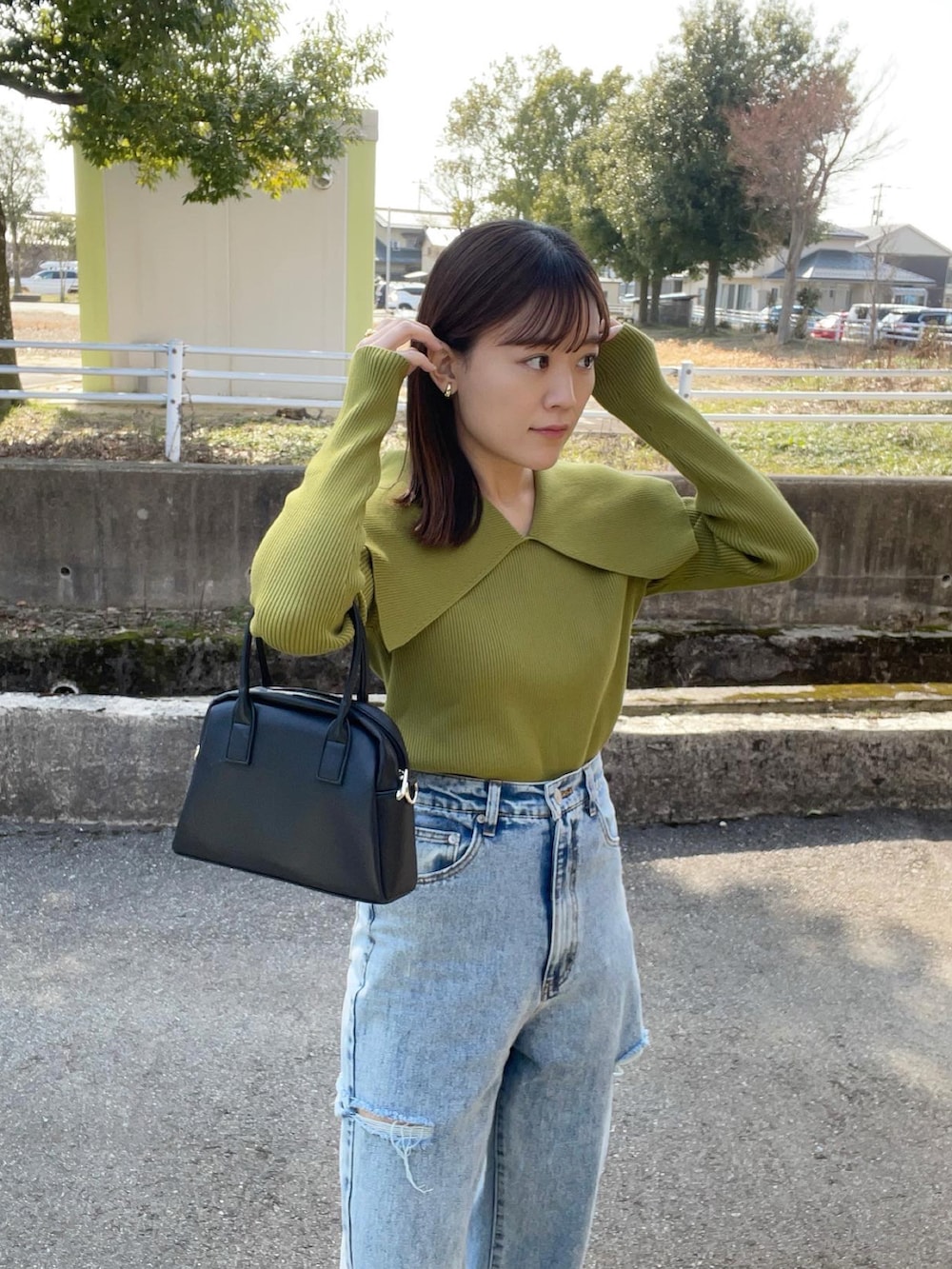 グリーン系のニット/セーター、その他のデニムパンツ、ブラック系のボストンバッグを着用したレディースの春コーディネートの3枚目の写真