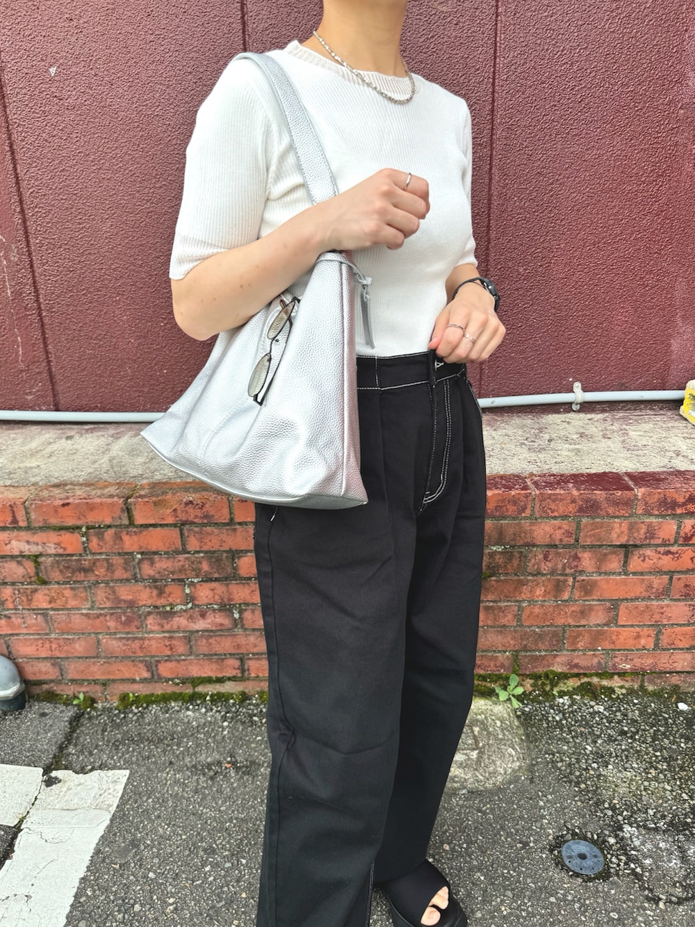 ホワイト系のニット/セーター、ブラック系のデニムパンツ、シルバー系のトートバッグを着用したレディースの夏コーディネートの2枚目の写真