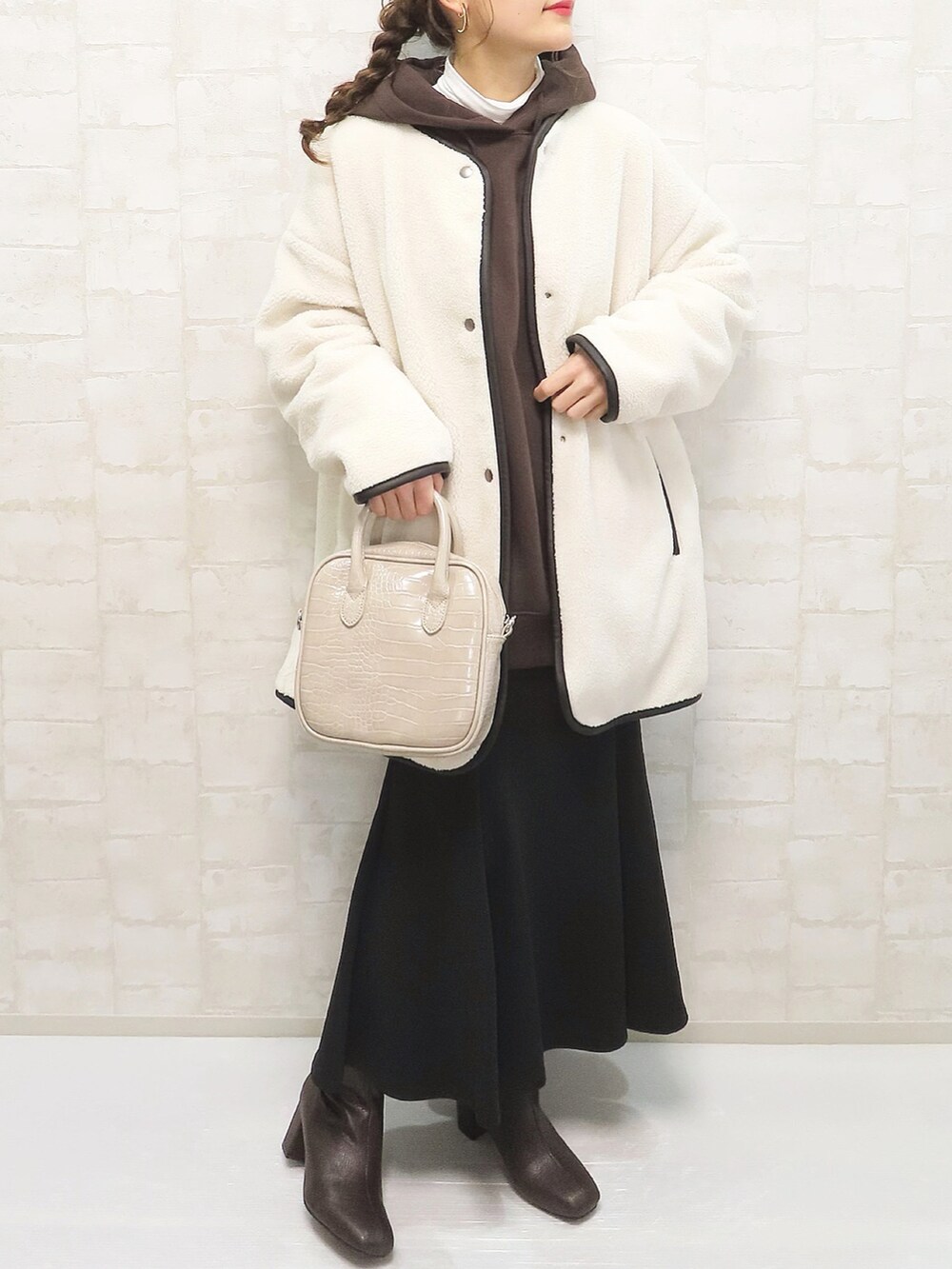 ブラウン系のパーカー、ブラック系のスカート、ホワイト系のその他アウターを着用したレディースの冬コーディネートの3枚目の写真