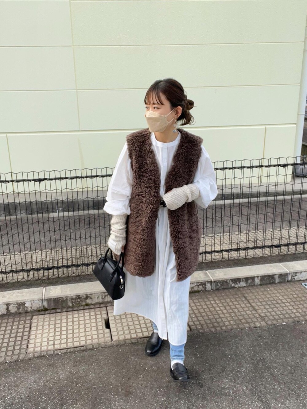 ホワイト系のシャツワンピース、ブラウン系のその他アウター、ブルー系のデニムパンツを着用したレディースの秋コーディネートの4枚目の写真