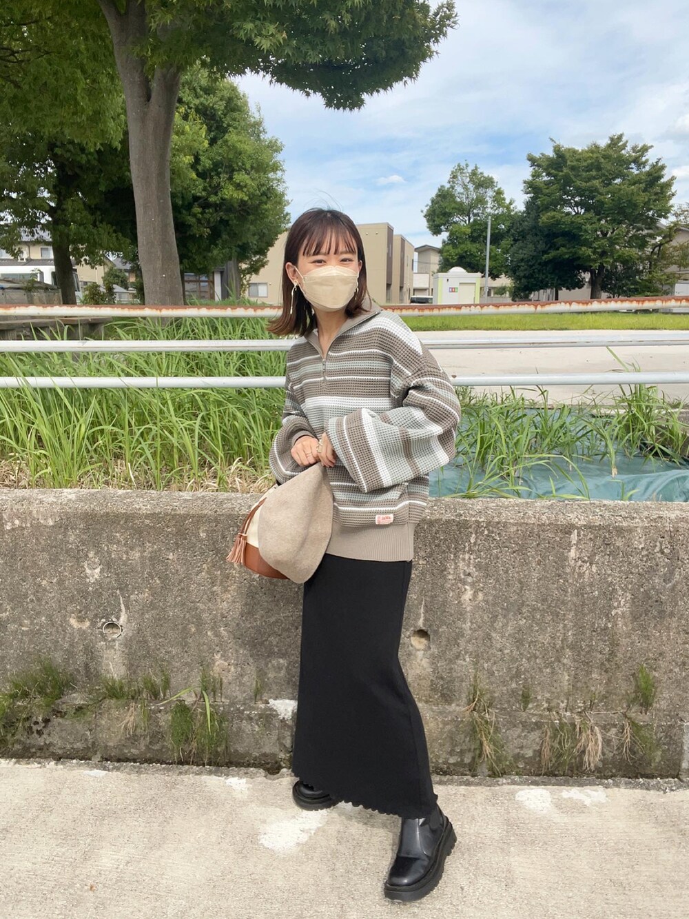 ブルー系のニット/セーター、ブラック系のワンピース、ブラウン系のショルダーバッグを着用したレディースの秋コーディネートの2枚目の写真