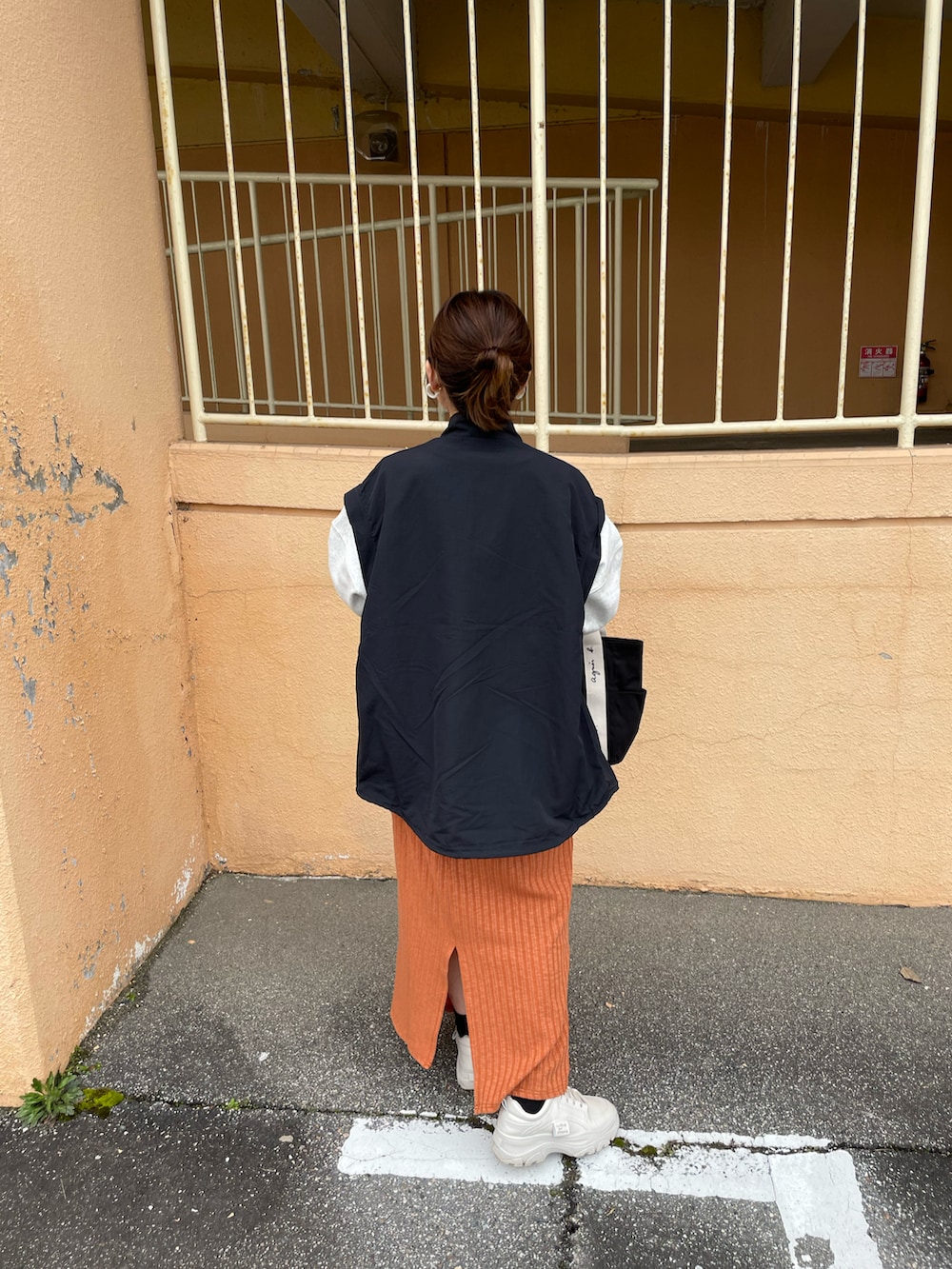 オレンジ系のスカート、ブラック系のマウンテンパーカー、グレー系のスウェットを着用したレディースの冬コーディネートの5枚目の写真