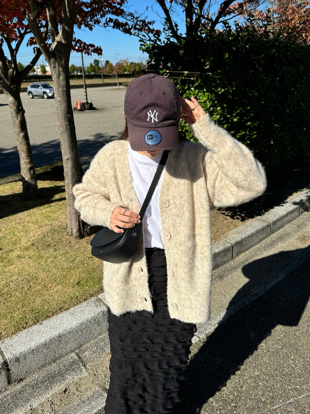 ベージュ系のカーディガン/ボレロ、ブラック系のスカート、ブラック系のショルダーバッグを着用したレディースの秋コーディネートの4枚目の写真