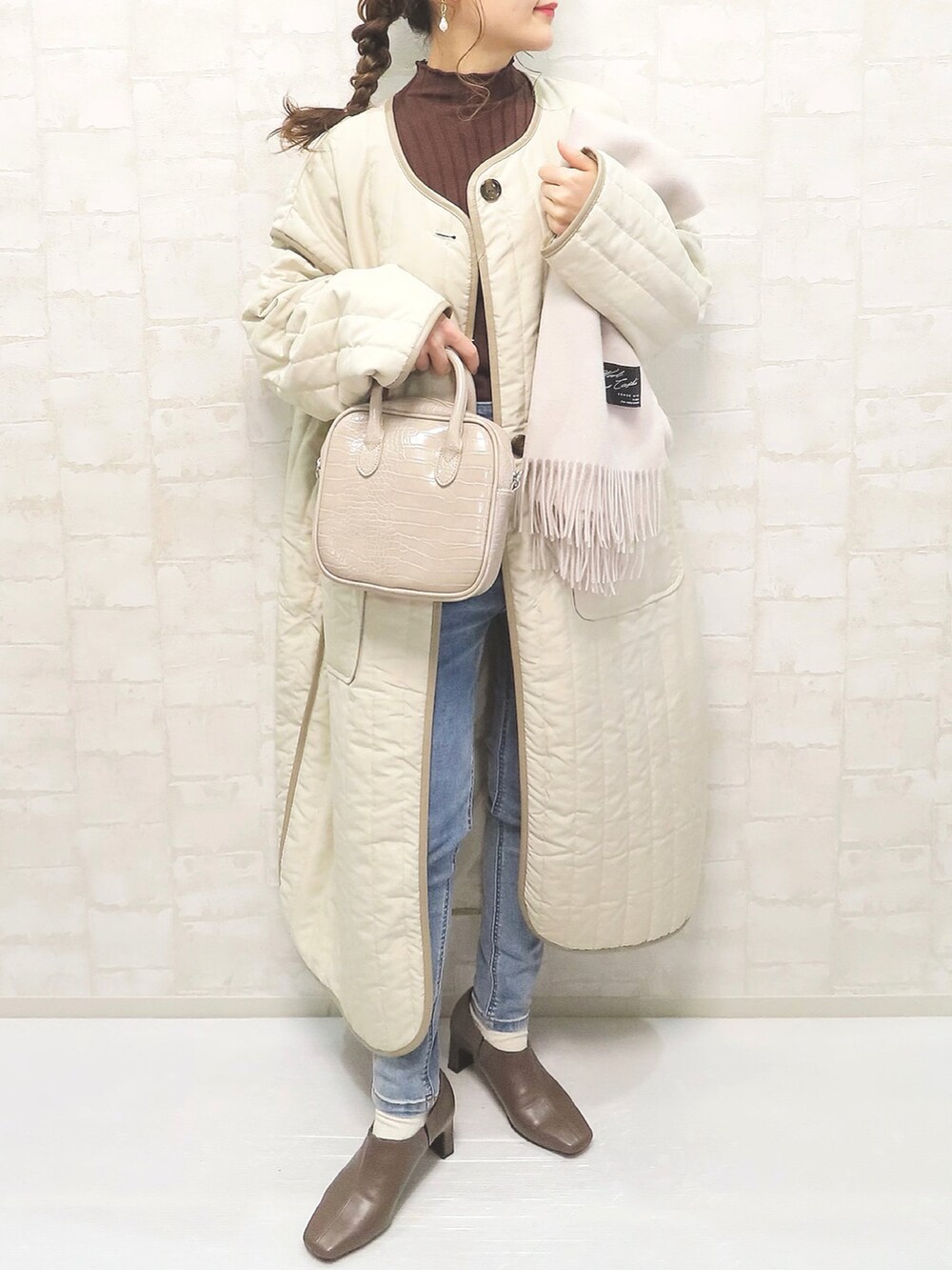 ベージュ系のノーカラーコート、ブラウン系のニット/セーター、ベージュ系のブーツを着用したレディースの冬コーディネートの3枚目の写真