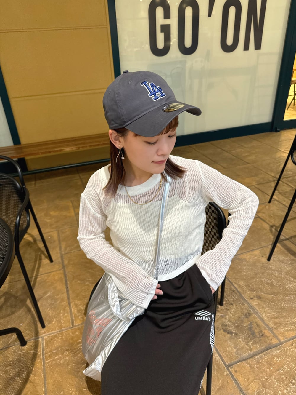 ホワイト系のトップス、ブラック系のスカート、シルバー系のトートバッグを着用したレディースの春コーディネートの3枚目の写真