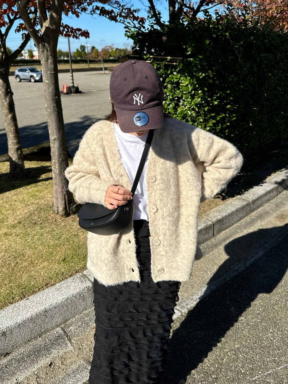 ベージュ系のカーディガン/ボレロ、ブラック系のスカート、ブラック系のショルダーバッグを着用したレディースの秋コーディネートの3枚目の写真