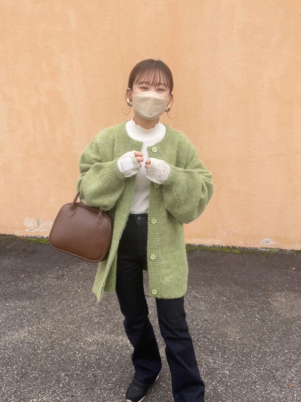 グリーン系のカーディガン/ボレロ、ホワイト系のニット/セーター、ブラウン系のショルダーバッグを着用したレディースの冬コーディネートの4枚目の写真