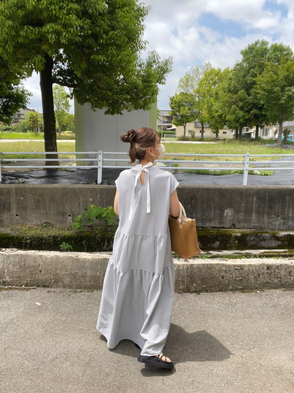 ブラック系のワンピース、ベージュ系のショルダーバッグ、ブラック系のサンダルを着用したレディースの夏コーディネートの2枚目の写真