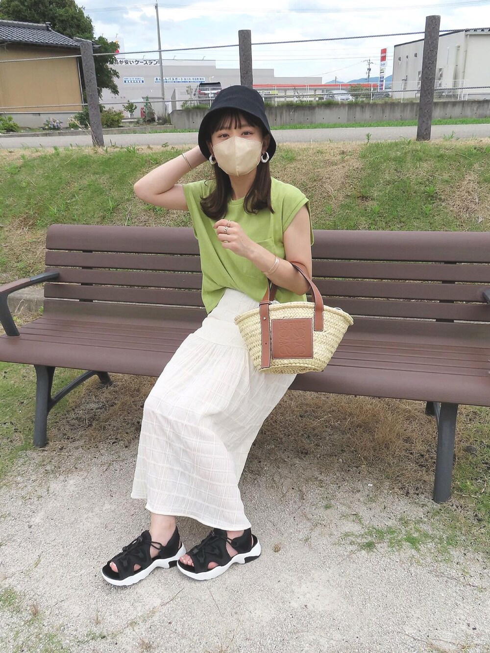 グリーン系のTシャツ/カットソー、ホワイト系のスカート、ベージュ系のかごバッグを着用したレディースの夏コーディネートの3枚目の写真