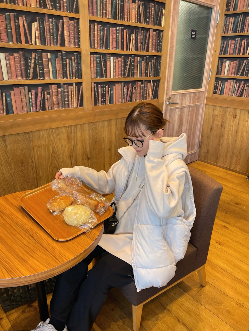 ホワイト系のパーカー、ホワイト系のベスト、ブラック系のショルダーバッグを着用したレディースの冬コーディネートの5枚目の写真