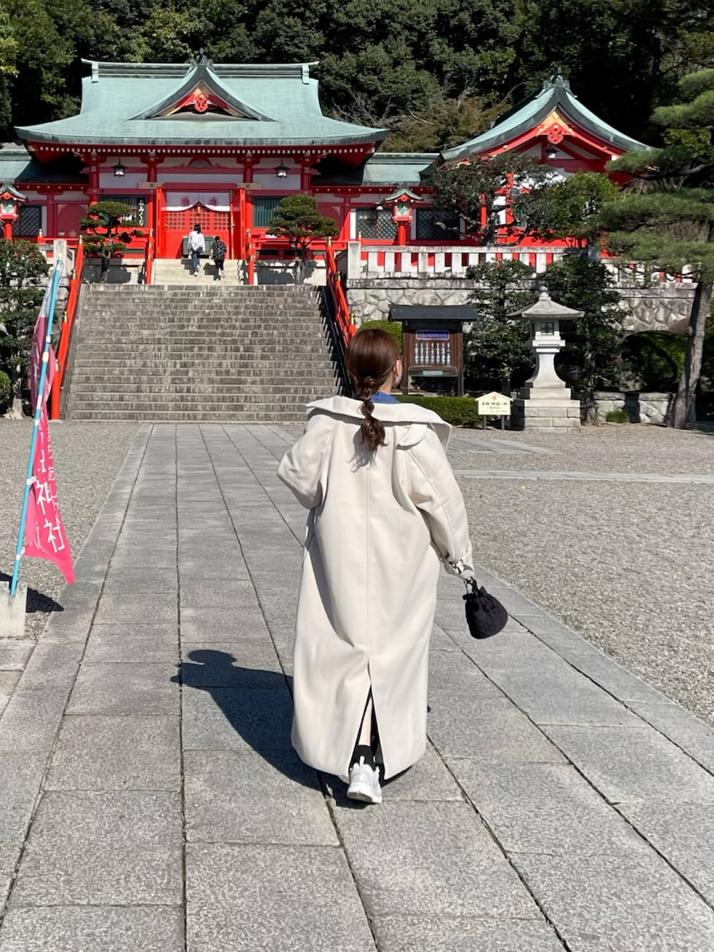 ホワイト系のトレンチコート、ブルー系のニット/セーター、ホワイト系のスニーカーを着用したレディースの秋コーディネートの4枚目の写真