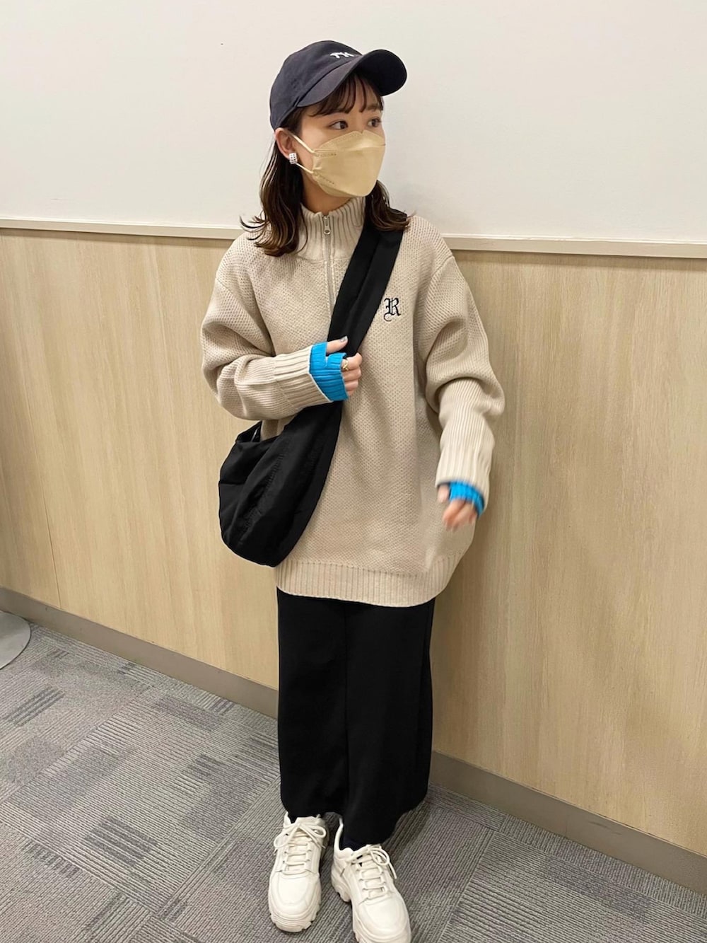 ベージュ系のニット/セーター、ブラック系のスカート、ブラック系のショルダーバッグを着用したレディースの春コーディネートの2枚目の写真