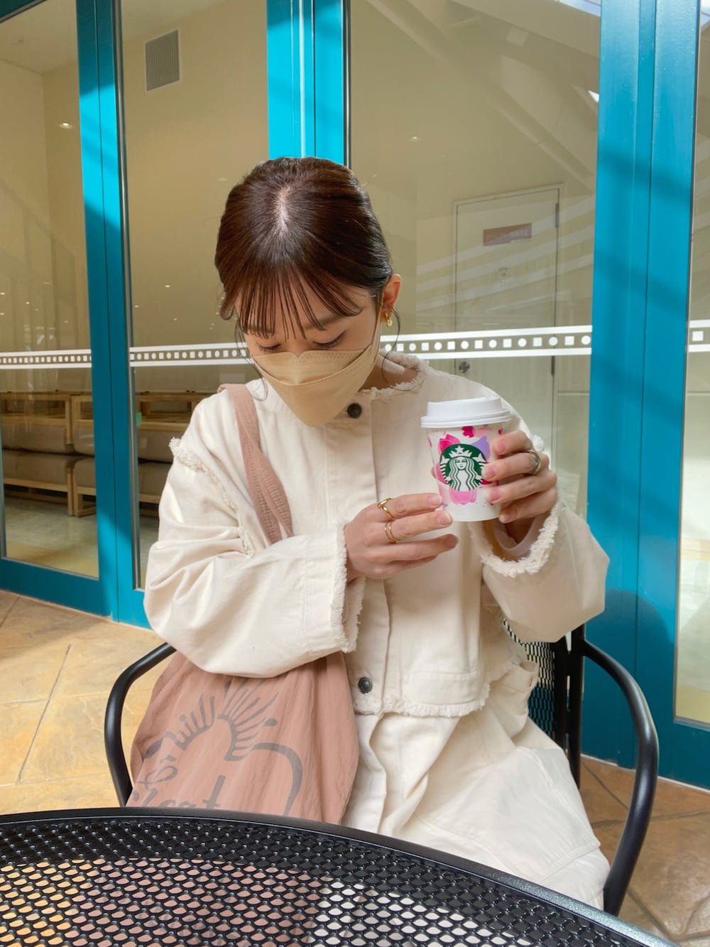 ピンク系のトートバッグ、ホワイト系のデニムジャケット、ホワイト系のスラックスを着用したレディースの春コーディネートの4枚目の写真