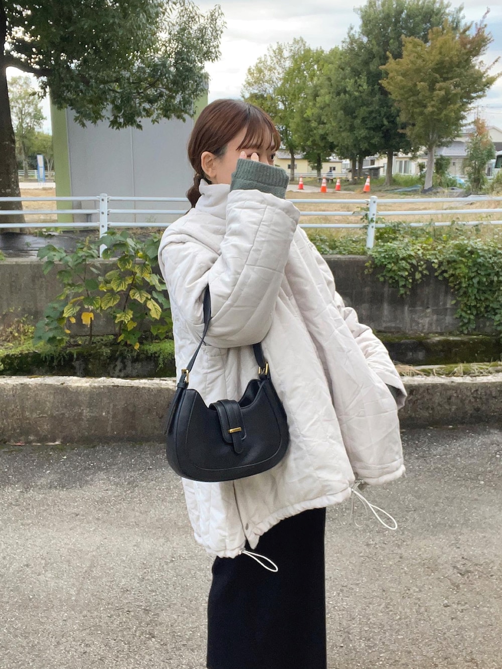 グリーン系のニット/セーター、ホワイト系のジャケット/アウター、ブラック系のバッグを着用したレディースの秋コーディネートの3枚目の写真