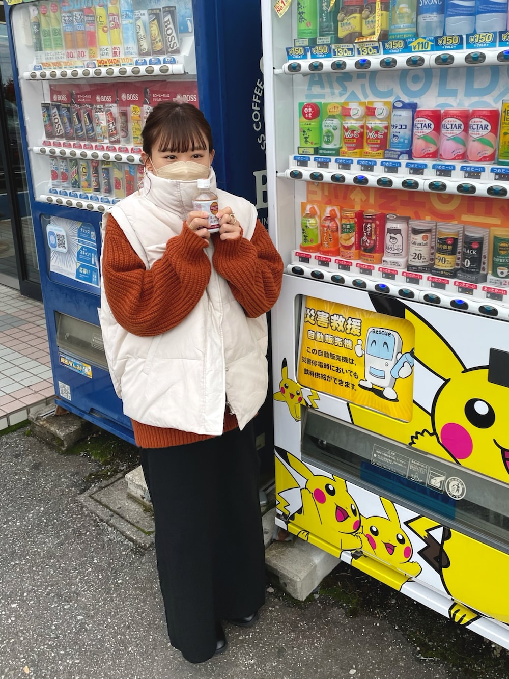 イエロー系のニット/セーター、ホワイト系のダウンベスト、ブラック系のスカートを着用したレディースの秋コーディネートの2枚目の写真