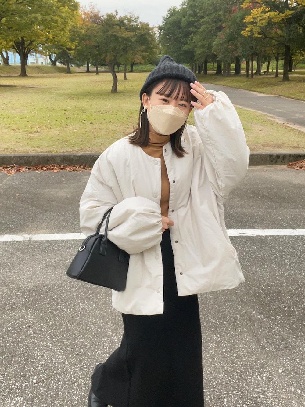 ホワイト系のダウンジャケット/コート、イエロー系のトップス、ブラック系のスカートを着用したレディースの秋コーディネートの5枚目の写真