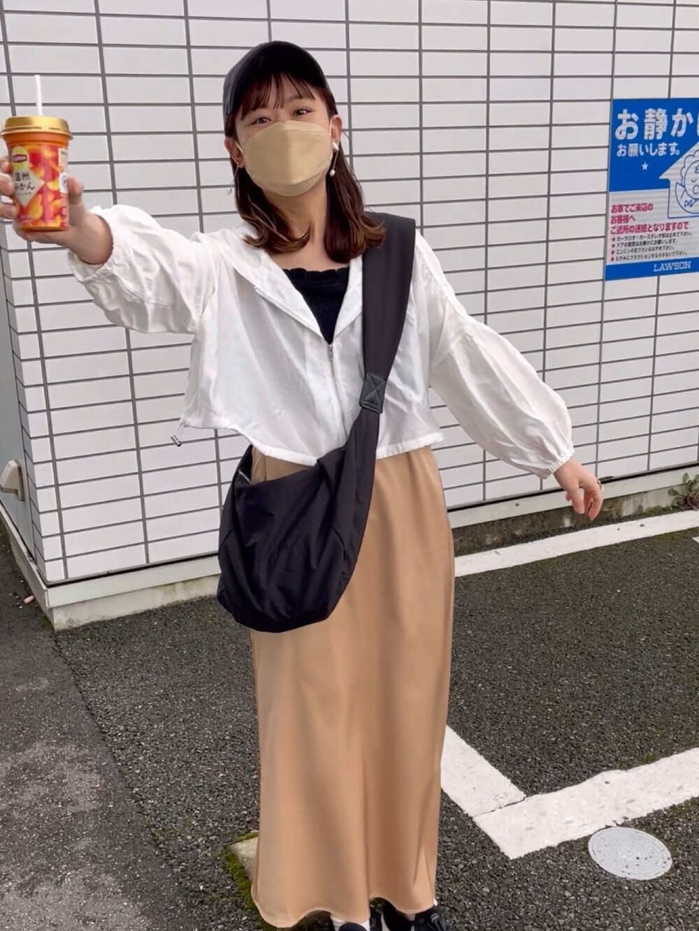 ベージュ系のスカート、ホワイト系のパーカー、ブラック系のキャミソールを着用したレディースの春コーディネートの3枚目の写真