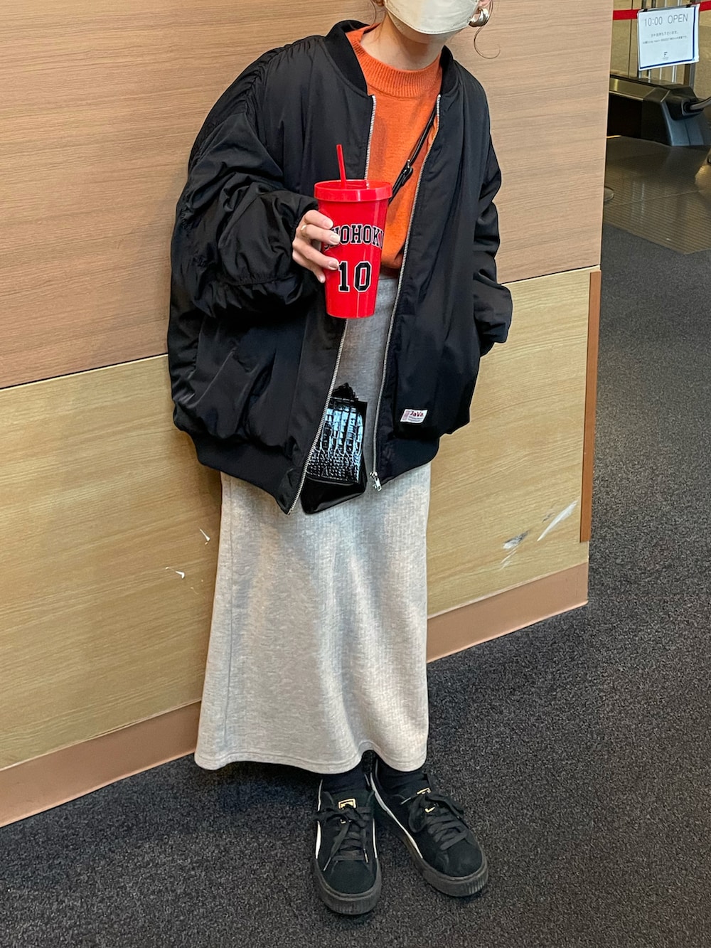 ブラック系のMA-1、オレンジ系のニット/セーター、ベージュ系のスカートを着用したレディースの冬コーディネートの2枚目の写真