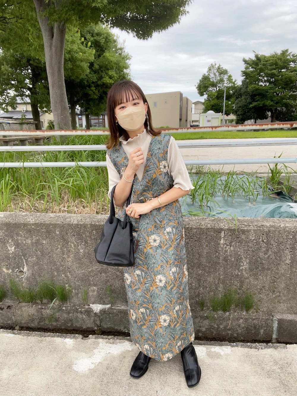 イエロー系のワンピース、ホワイト系のTシャツ/カットソー、ブラック系のハンドバッグを着用したレディースの秋コーディネートの2枚目の写真