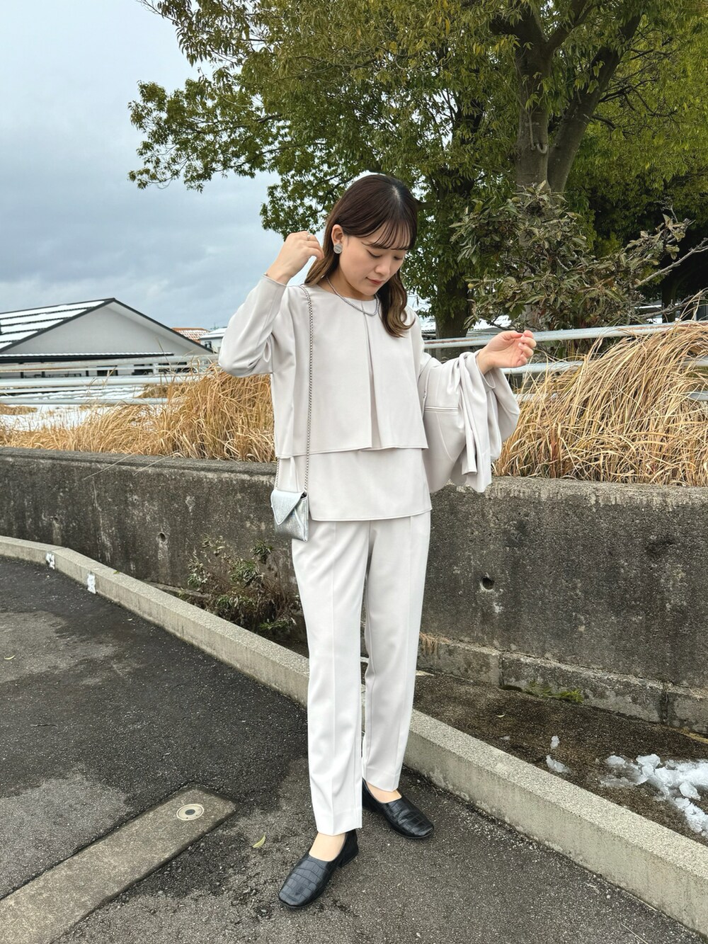 ベージュ系のセットアップ、ブラック系のパンプス、ベージュ系のパンツドレスを着用したレディースの冬コーディネートの2枚目の写真