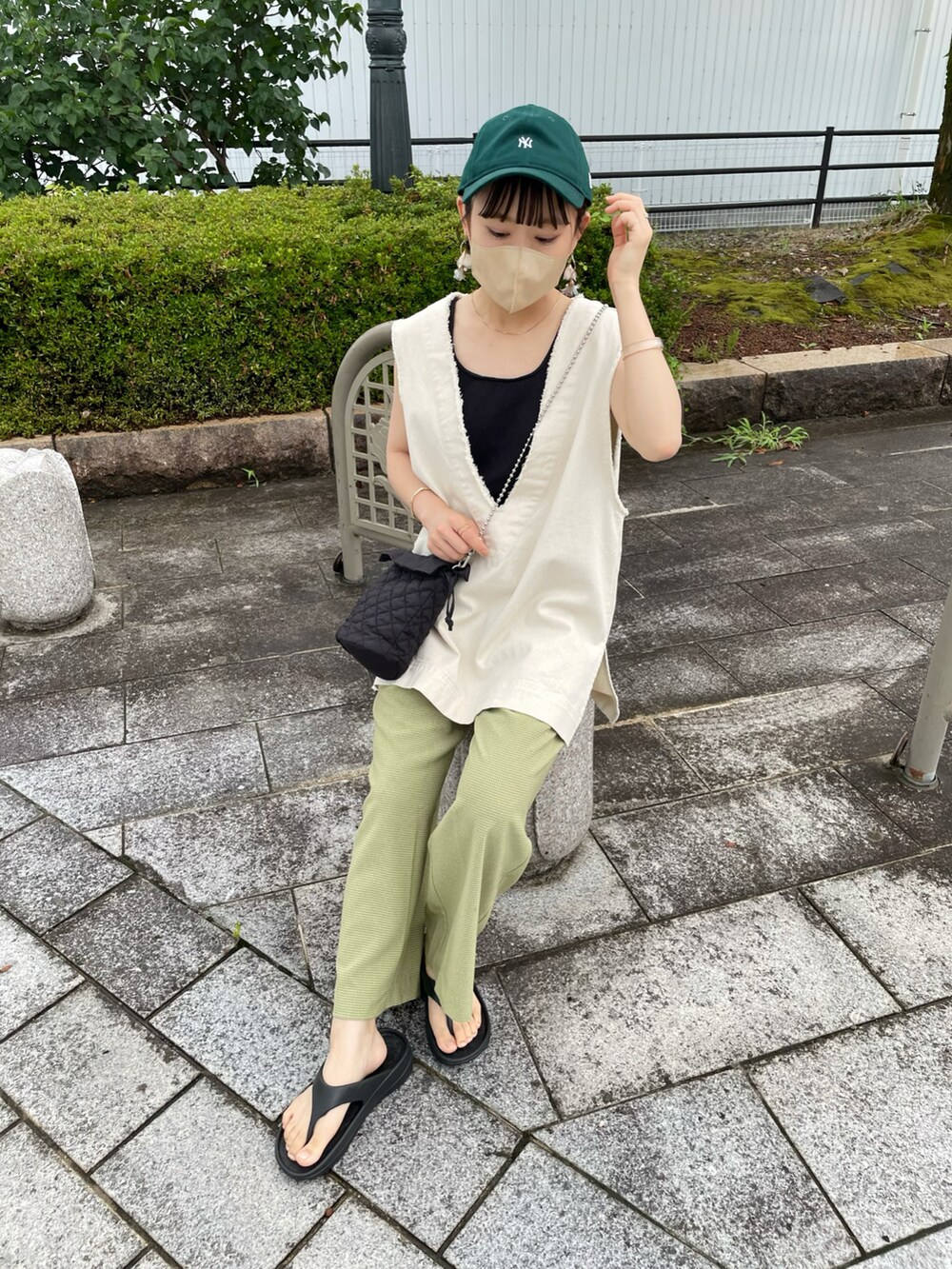 グリーン系のその他パンツ、ホワイト系のベスト、ブラック系のショルダーバッグを着用したレディースの夏コーディネートの3枚目の写真