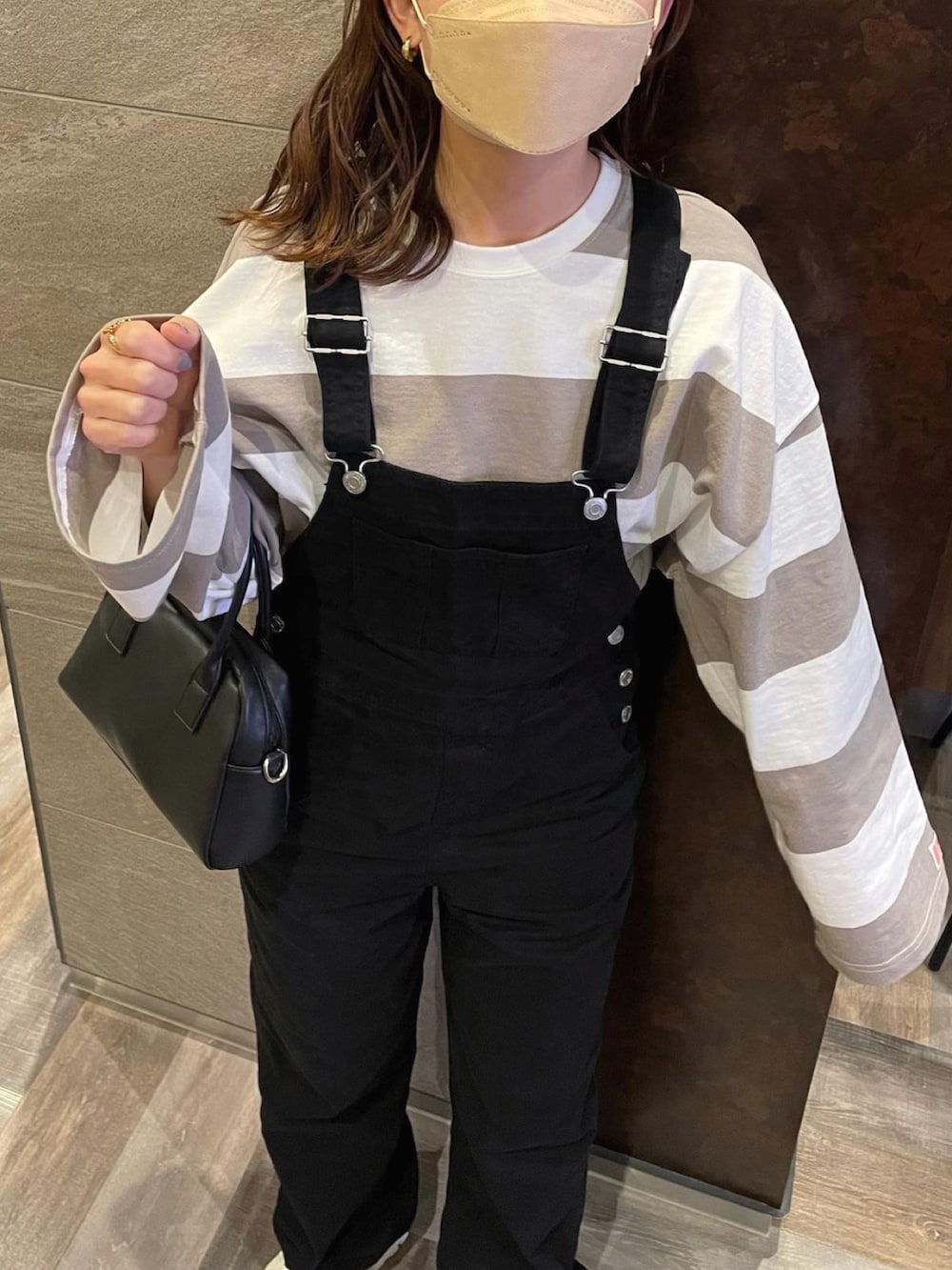 ブラック系のサロペット/オーバーオール、ベージュ系のTシャツ/カットソー、ホワイト系のスニーカーを着用したレディースの冬コーディネートの4枚目の写真