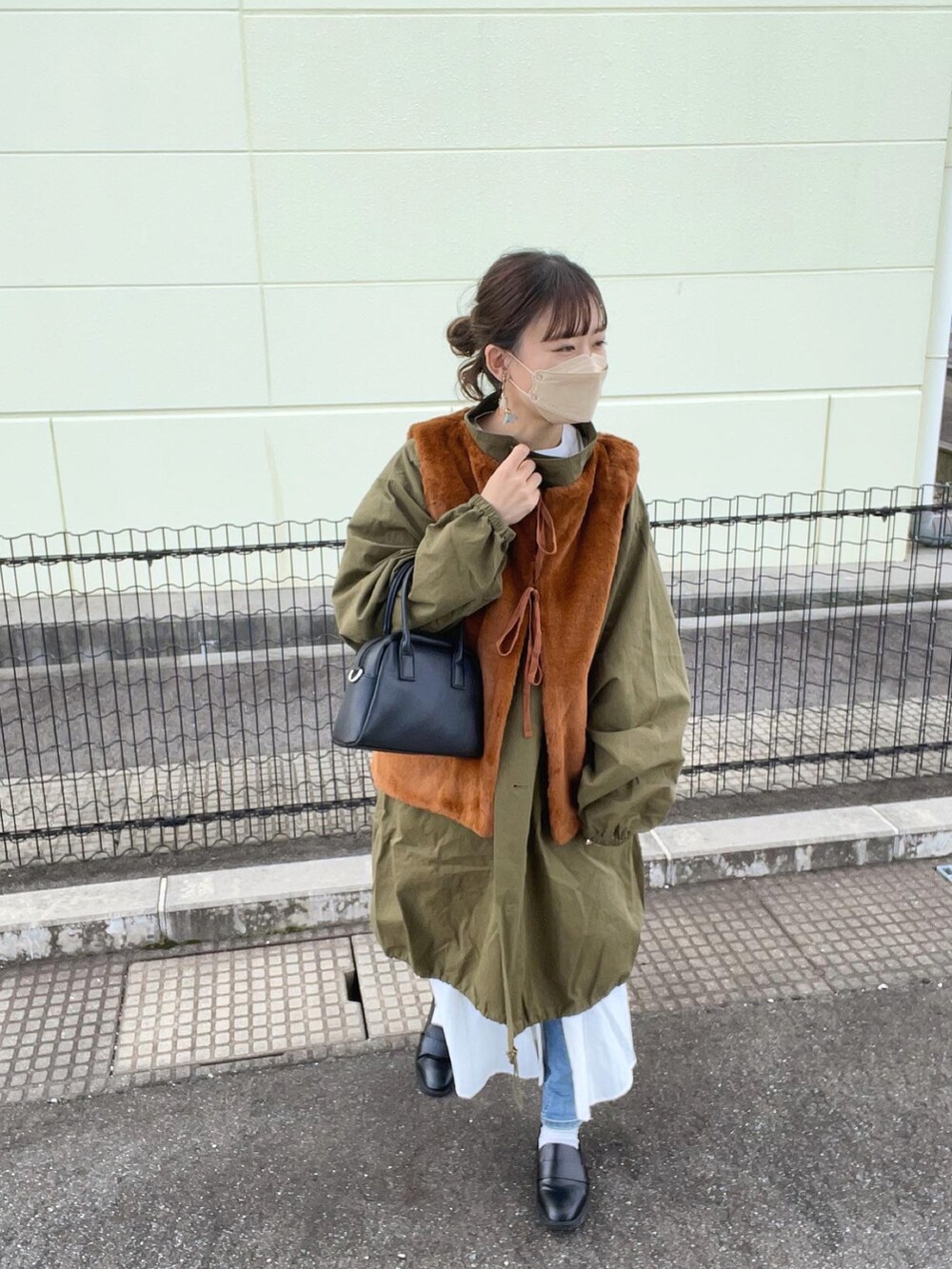 グリーン系のモッズコート、ホワイト系のシャツワンピース、ブラック系のボストンバッグを着用したレディースの秋コーディネートの3枚目の写真